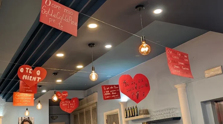 Biglietti a forma di cuore con frasi in dialetto napoletano appesi in sala